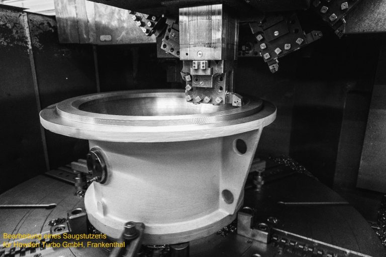 Maschine zur metallbearbeitung mit einem großen, runden Werkzeug in Schwarz-Weiß.